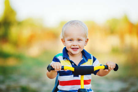 Portrait of a smiling boy a children s Bicycle in a green Parkの写真素材