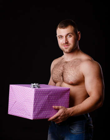 Image of muscular man holding xmas gifts, isolated on blackの写真素材