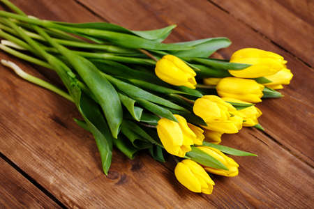 Beautiful bouquet of yellow tulips lying on wooden backgroundの写真素材
