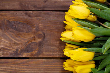 Beautiful bouquet of yellow tulips lying on wooden backgroundの写真素材