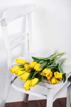 Beautiful bright yellow tulips in Still Life lying on antique white Chairの写真素材