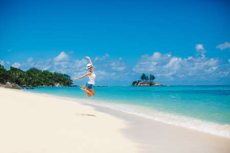 summer and holiday concept - laughing woman jumping on the beachの写真素材