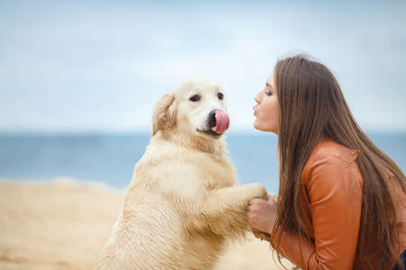 portrait of Beautiful woman with her dog on the beach near seaの写真素材
