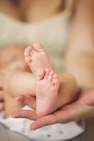 Tiny Newborn Baby s feet on mother's hands closeup  Mom and her Child.  Beautiful Conceptual image...