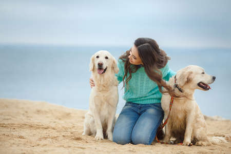 Beautiful woman with her dog playing on the sea shore 