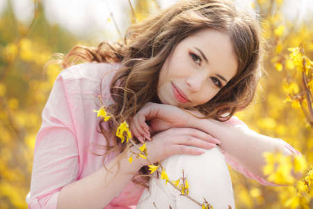Closeup portrait of cute young girl with yellow flowers smiling outdoorsの写真素材