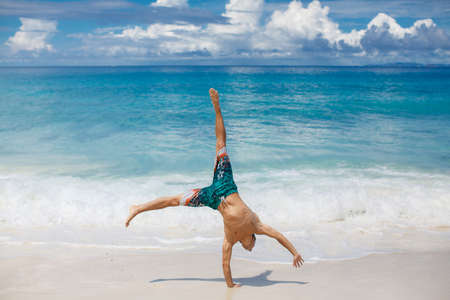 Happy outdoor young man doing wheel on the beach  Healthy and active lifestyle shot expressing...