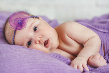 Caucasian baby boy covered with pink towel joyfully smiles at cameraの写真素材