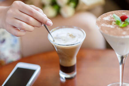 Woman is sitting in cafe, drinking coffee and phone callingの写真素材