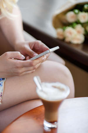 Woman is sitting in cafe, drinking coffee and phone callingの写真素材