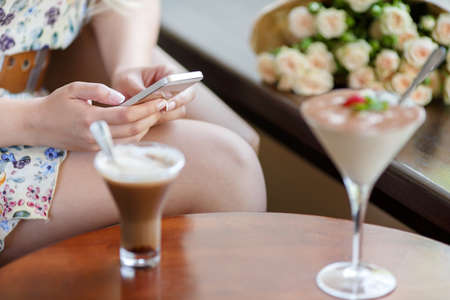 Woman is sitting in cafe, drinking coffee and phone callingの写真素材
