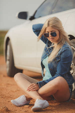 close up portrait of Young pretty blonde lady with a modern luxury car