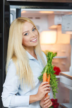 Healthy Eating Concept  Diet  Beautiful Young Woman near the Fridge with healthy food  Fruits and Vegetables in the Refrigerator  Vegan foodの写真素材