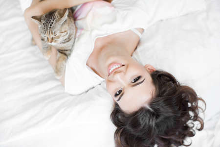 Woman in underwear relaxing and playing on bed with her cat on the summer warm day の写真素材