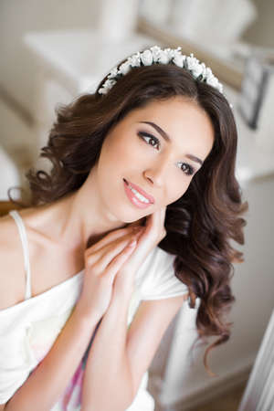 Beautiful young bride with wedding makeup and hairstyle in bedroom, attractive newlywed woman have final preparation for wedding  Happy Bride waiting groom  Marriage Wedding day moment  Bride portraitの写真素材