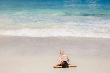 Cute woman relaxing on the tropical beach  young woman is laying at the tropical sand beach 