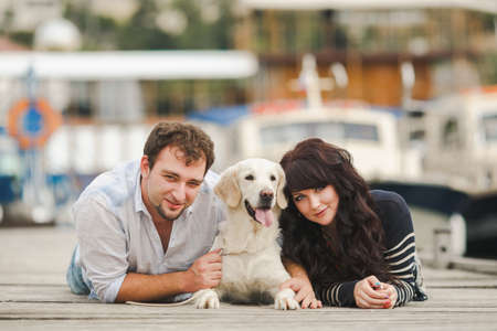 Young couple with dog posing at historical town sunny day  Couple playing with their dog in harborの写真素材