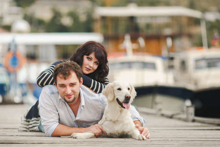 Young couple with dog posing at historical town sunny day  Couple playing with their dog in harborの写真素材