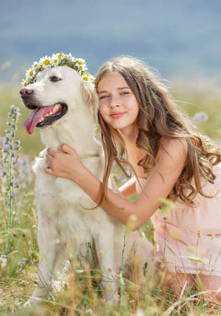 Beautiful woman playing with her dog  Outdoor portrait  series  Woman embraces golden retriever lying on the green grass  Woman playing with her dog outdoorsの写真素材