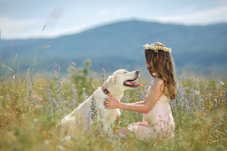 Beautiful woman playing with her dog  Outdoor portrait  series  Woman embraces golden retriever lying on the green grass  Woman playing with her dog outdoorsの写真素材