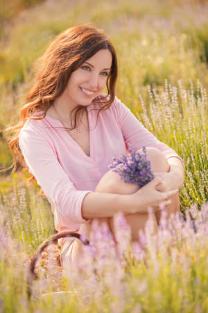 Beautiful girl on the lavender field  smiling beautiful brunette in the lavender field の写真素材