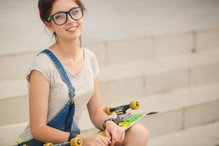 Beautiful young woman with skateboard in city