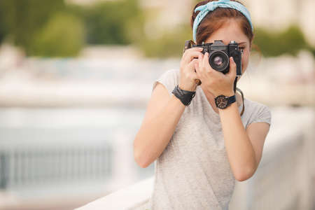 Young woman with camera outdoors portrait  Soft sunny colors  woman with vintage retro camera having fun playful laughingの写真素材