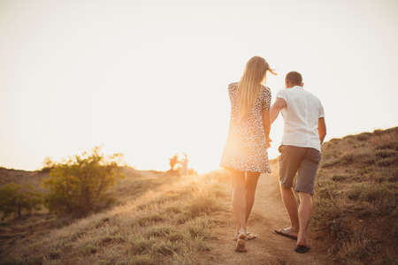 Young couple in love, an attractive man and woman enjoying a romantic evening, holding hands to watch the sunsetの写真素材
