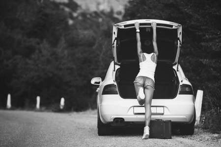 Woman with head getting into the opened car trunk