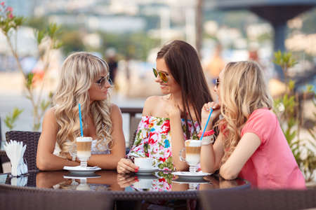 Group Of Women Meeting In Cafe. holidays, tourism, technology and internet - three beautiful girls. Three Women Enjoying Cup Of Coffee In Cafe.の写真素材