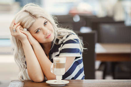 Young woman enjoying a cafe latte in a summer Cafe. woman drinking coffee in the morning.の写真素材