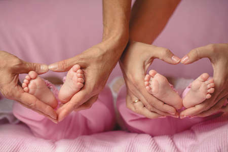 Legs tiny newborn child at the hands of women