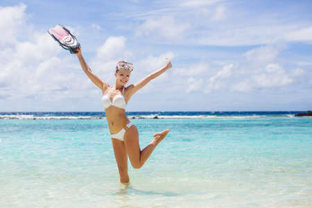 close portrait of Young woman with wet skin and with a snorkeling equipment on sand and going to...