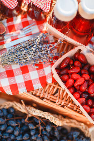 Different berries in a wicker basket with juice on the home desktop.