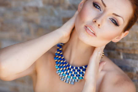 Portrait Of Young Smiling Beautiful Woman. Stunning young woman posing outdoor over brick wall. Portrait of a beautiful womanの写真素材