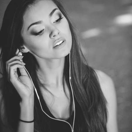 Black and white fashion portrait of a woman listening to music on headphones.の写真素材