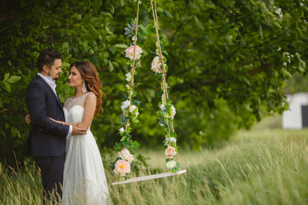 Beautiful young wedding pair in park, the bride in a white wedding dress on fluctuation and her groom.の写真素材