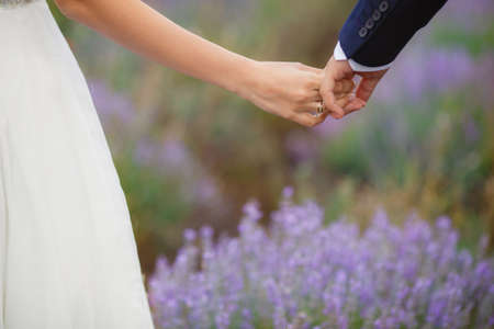A young couple in love bride and groom, wedding day in summer. Enjoy a moment of happiness and love in a lavender field. Bride in a luxurious wedding dress on a background bright blue sky .の写真素材