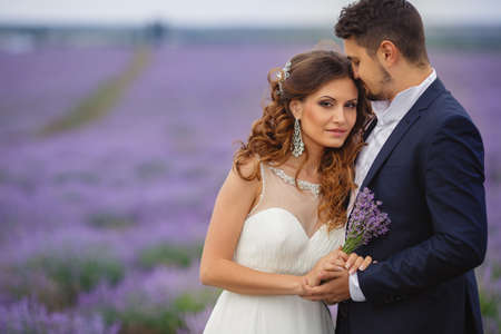 Closeup portrait of the bride and groom in wedding attire, enjoying the love Sunny summer day on the blooming lavender fields.の写真素材