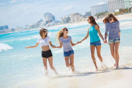 Beautiful girls are photographed on a tropical resort on the background of the beach and ocean.Four beautiful young girls brunette long straight hair, wearing shorts and t-shirts, sun glasses, with a beautiful smile, having fun and having fun, posing forの写真素材