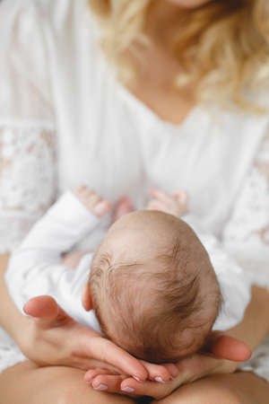 Mother holding head of her newborn son in hands. The baby on hands at mum. Loving mother hand holding cute sleeping newborn baby childの写真素材