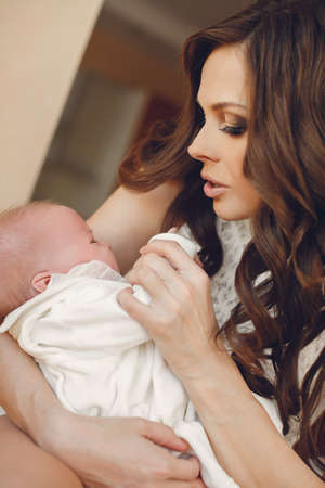 Mother holding head of her newborn son in hands. The baby on hands at mum. Loving mother hand...