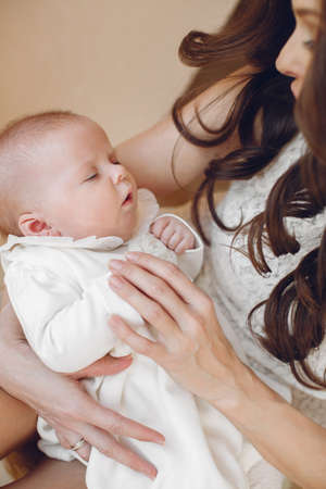 Mother holding head of her newborn son in hands. The baby on hands at mum. Loving mother hand...