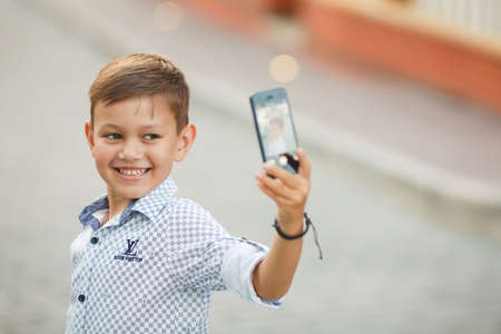 Young boy making selfie pictures with smart phone with shallow depth of fieldの写真素材