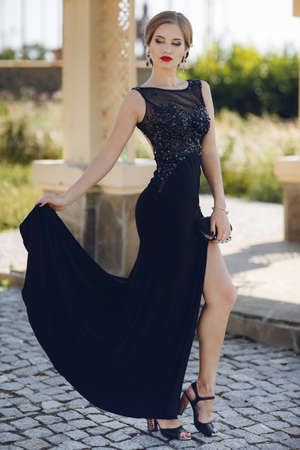 Fashion outdoor photo of beautiful sensual woman in luxurious sequin dress posing in summer park. fashion photo of beautiful tender woman with dark hair in elegant dress posing in summer gardenの写真素材