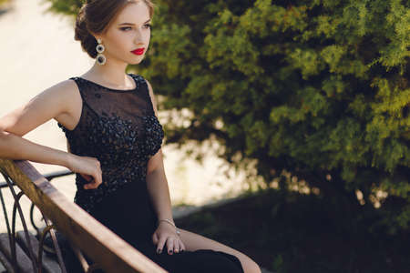 Fashion outdoor photo of beautiful sensual woman in luxurious sequin dress posing in summer park. fashion photo of beautiful tender woman with dark hair in elegant dress posing in summer gardenの写真素材