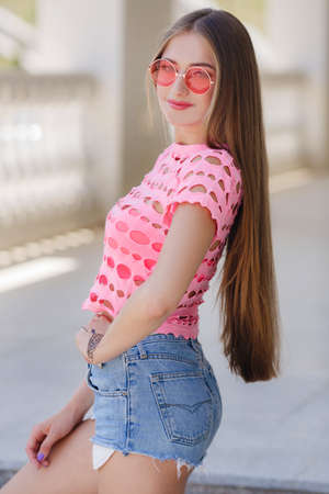 Portrait of the young beautiful smiling woman outdoors enjoying summer sunの写真素材