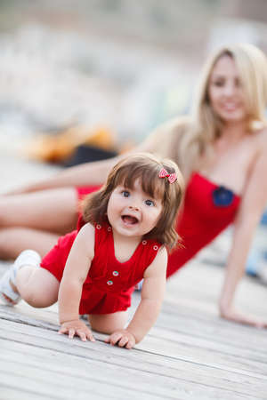 Mother playing with child baby girl outdoor by the sea. Fun and joy. Happy family. Woman with child. Smiling girl. Sea styleの写真素材