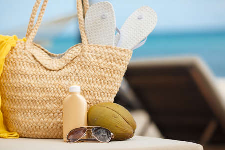 Vacation. Summer on tropical island. Straw bag, flip flops, sunglasses, sun lotion on beach background. Summer trip, traveling. Travelの写真素材