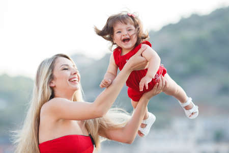 Mother and daughter having fun on wooden bridge by the sea. Happy Family by the Sea. mother playin with baby girl. Woman with child in marine sea styleの写真素材